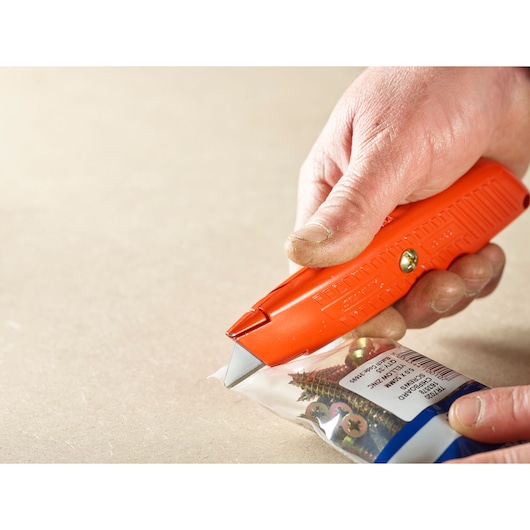 STANLEY 0-10-189 orange utility knife cutting a plastic bag of screws, close-up photography.