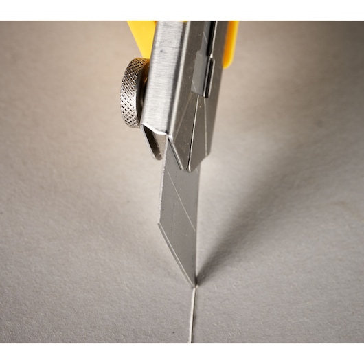 STANLEY 0-11-725 utility knife cutting gray cardboard, close-up photography.