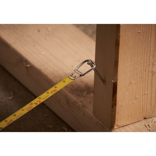 Photo of STANLEY 0-34-102 tape measure hooked on a nail in wood, close-up of measuring in progress.