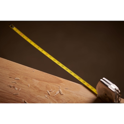 STANLEY 0-39-055 tape measure extended on wood surface with wood shavings, side angle photography.