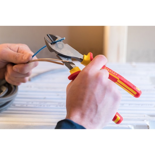 Stanley 0-84-004 insulated diagonal cutting pliers used to cut electrical wires, close-up in hand.