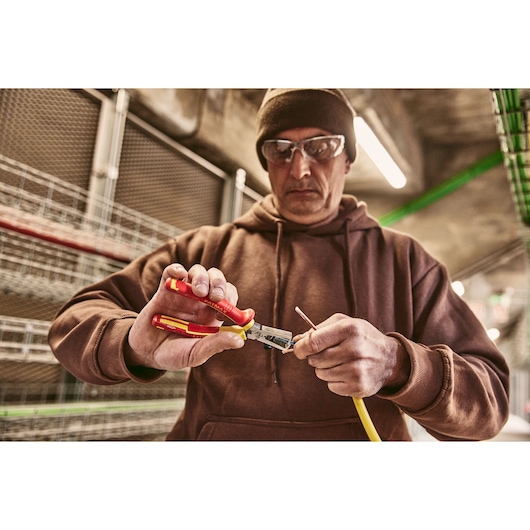 Stanley 0-84-010 insulated pliers used to strip wire, close-up photo in industrial setting.