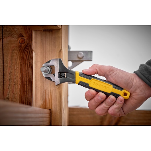 STANLEY 0-90-949 adjustable wrench with yellow and black handle used on a bolt attached to wooden beams.