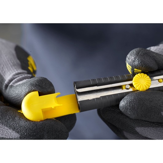 STANLEY 1-10-409 utility knife in black and yellow held by gloved hands, close-up angle.