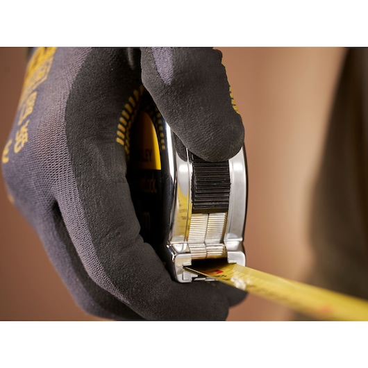 STANLEY 1-33-191 tape measure held by a gloved hand, close-up angle.