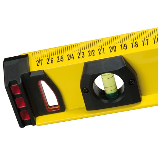 Close-up of a yellow spirit level with a ruler scale and bubble vial for measuring angles and alignment.