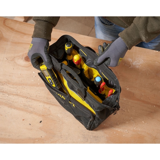 STANLEY 1-93-330 tool bag filled with assorted hand tools, top view, on wooden surface.
