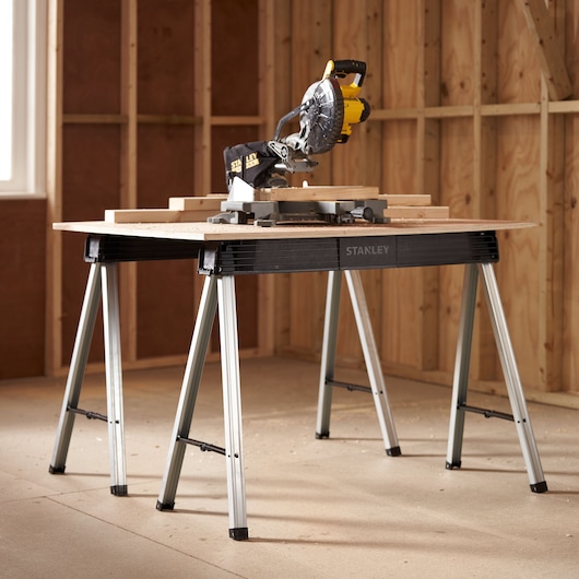 STANLEY 1-97-475 folding workbench with metal legs, shown in a workshop with a miter saw on top.
