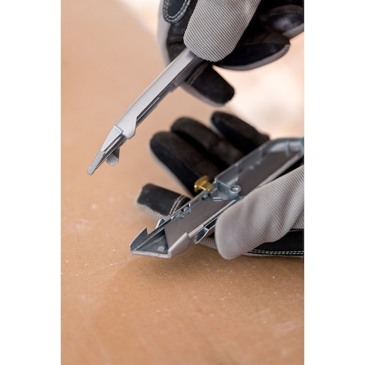 Photo of gloved hands opening a STANLEY 2-10-099 utility knife on a work surface.