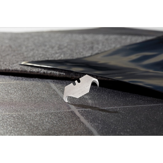 STANLEY 2-11-983 utility blade on a textured black surface, close-up angle, product photography.
