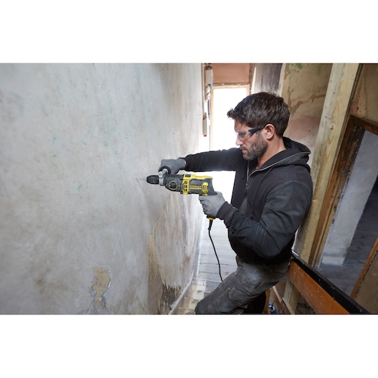 Photo of a person drilling a wall with a STANLEY FMEH850K corded hammer drill.
