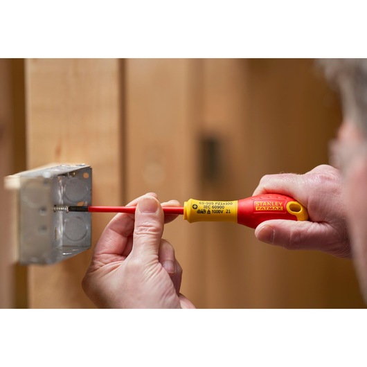Stanley FMHT0-62649 insulated screwdriver used to tighten screw in metal electrical box, close-up view.