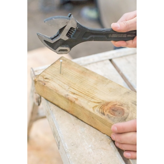 STANLEY FMHT0-75081 adjustable wrench used on nail in wooden plank, close angle.