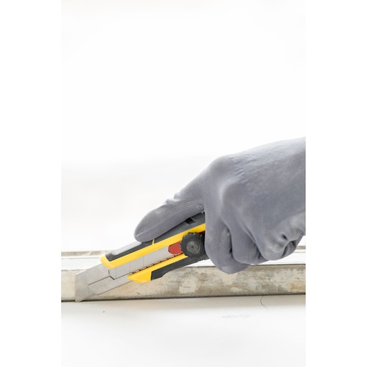 Photo of STANLEY FMHT10330-0 utility knife in gloved hand cutting along a metal guide.