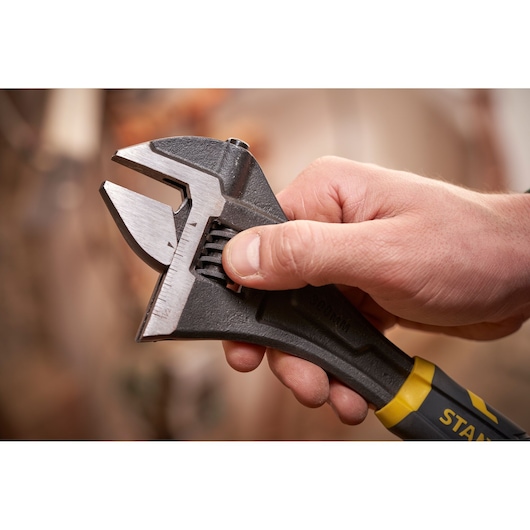 STANLEY FMHT13126-0 adjustable wrench held in hand, close-up on metal jaw and yellow-black handle.