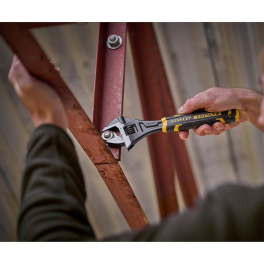 STANLEY FMHT13128-0 adjustable wrench, FATMAX series, used on a metal bolt, close-up photography.