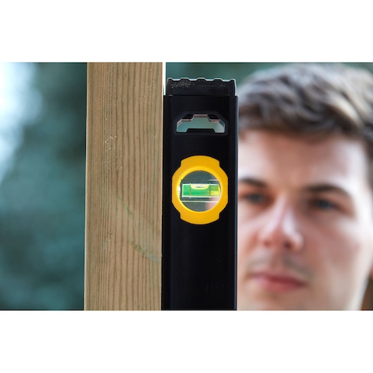 Photo of STANLEY FMHT42562-1 spirit level with yellow accents measuring a vertical wooden post.