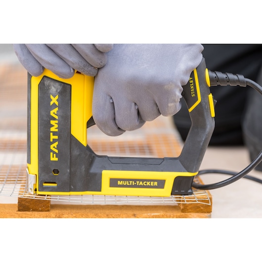 STANLEY FMHT6-75934 multi-tacker tool in use, yellow and black, close-up side angle.