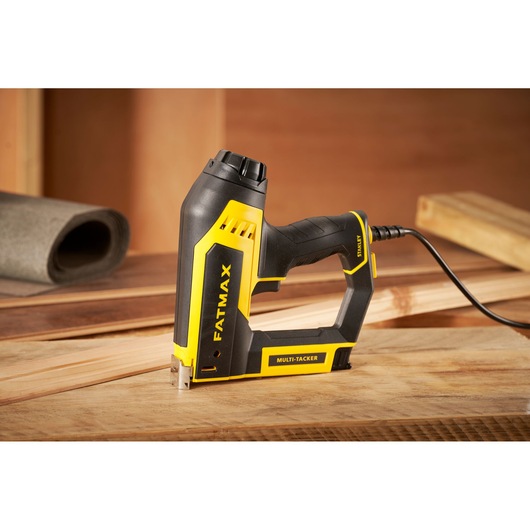 STANLEY FMHT6-75934 electric multi-tacker, black and yellow, side angle, on wooden workspace.