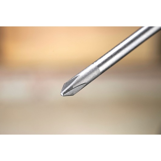 Close-up of a metal Phillips screwdriver tip against a blurred background.