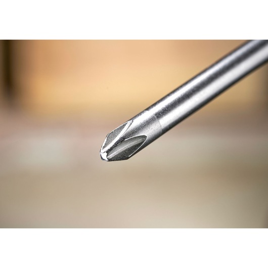 Close-up of a metal Phillips screwdriver tip with a blurred background.