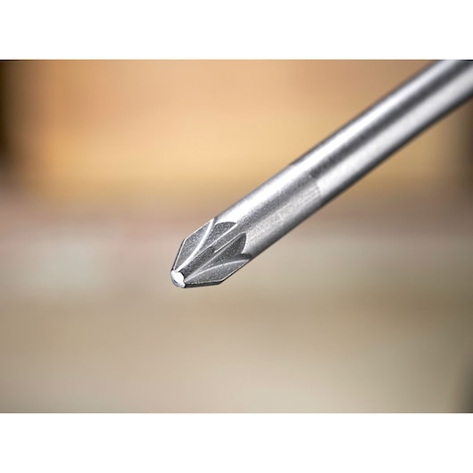 Close-up of a metallic Phillips screwdriver tip against a blurred background.