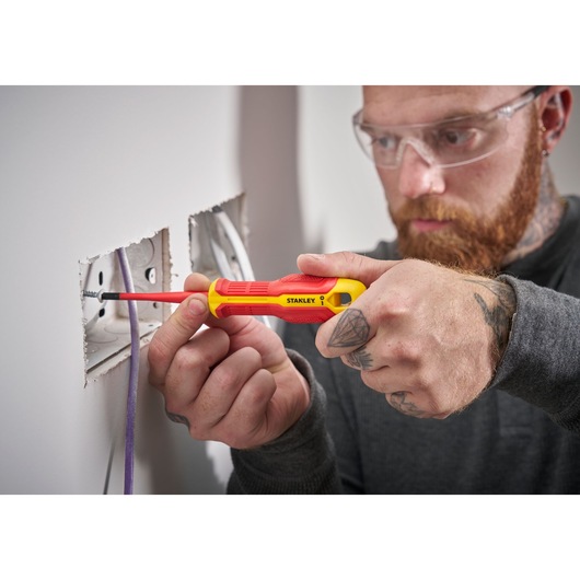 Person uses a STANLEY insulated screwdriver to install a screw in a wall electrical outlet.