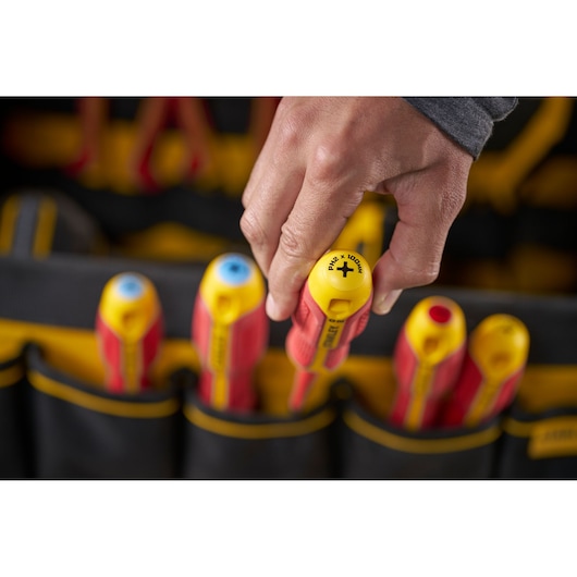 Hand picking a STANLEY insulated screwdriver from a tool pouch with other screwdrivers visible.