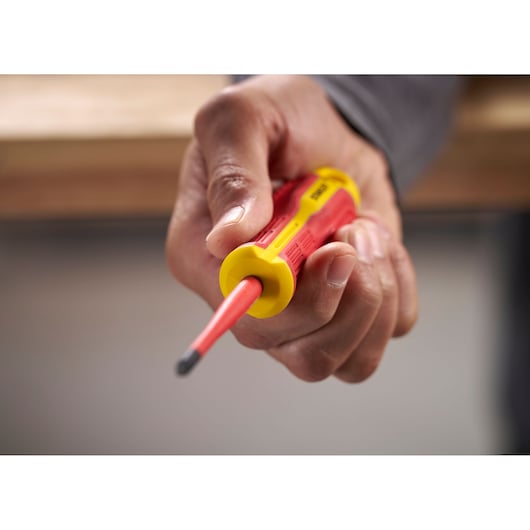 Hand holding a STANLEY insulated screwdriver with red and yellow handle close up.