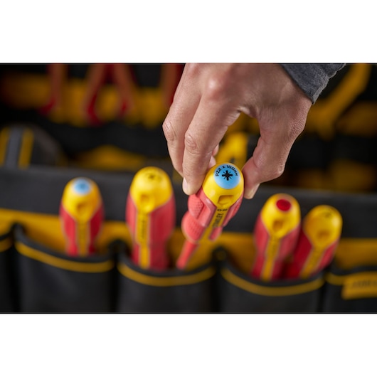 Hand selects an insulated screwdriver from a tool bag with other screwdrivers. STANLEY branding visible.