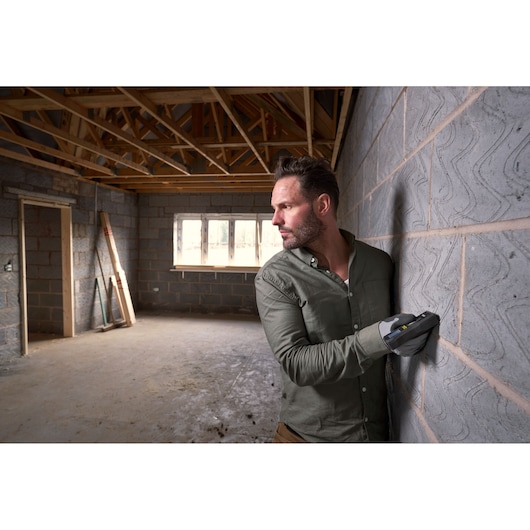 STANLEY FMHT77165-0 digital wall scanner used on stone wall in unfinished construction site.