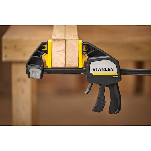 Photo of STANLEY FMHT83282-0 trigger clamp securing wooden boards on workbench.