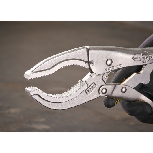 Close-up of a STANLEY locking pliers, showing serrated jaws and handle held by a gloved hand.