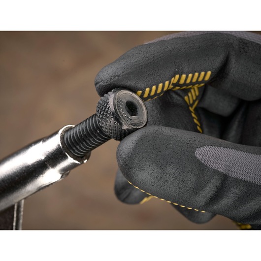 Gloved hand holding a black threaded bolt with knurled head, showcasing STANLEY tool detail.
