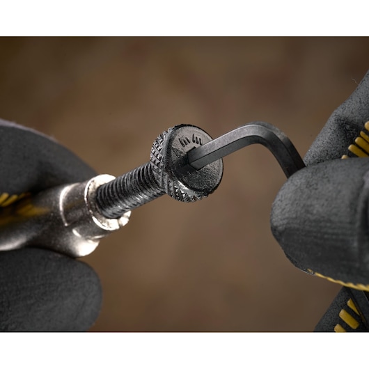 Close-up of gloved hands using an Allen key to tighten a textured bolt.