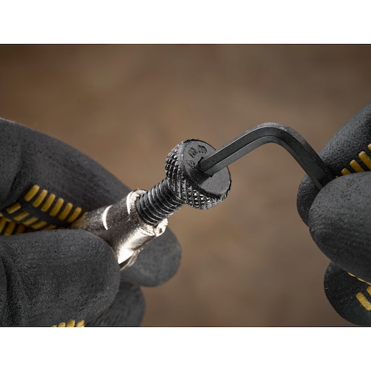 Gloved hands using an Allen key to tighten or loosen a knurled screw, close-up view of the action.