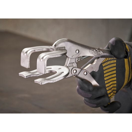 A person holds a STANLEY C-clamp locking plier, designed for clamping and welding tasks, in a work glove.