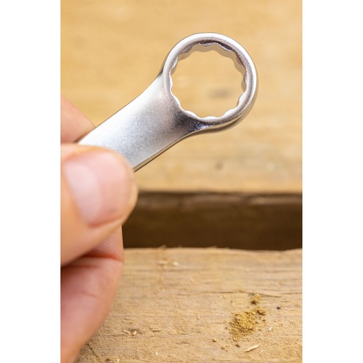 STANLEY FMMT13035-0 box-end wrench close-up, silver finish, held by hand above wooden surface.