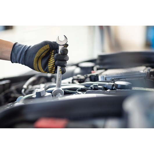 Photo of STANLEY FMMT13068-0 wrench in gloved hand using it on car engine, automotive tool.