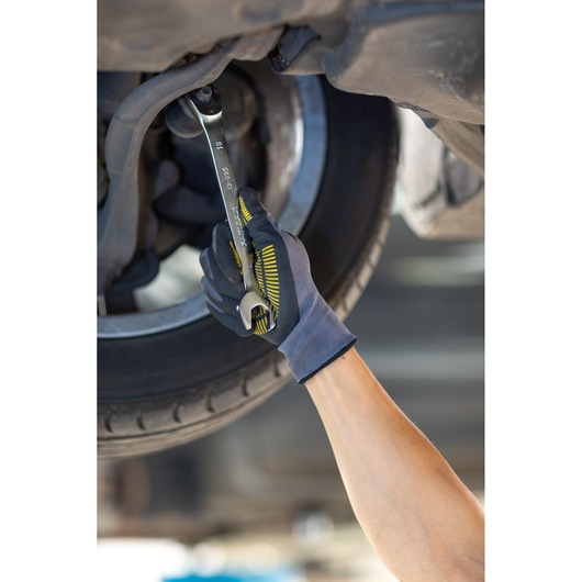 Stanley FMMT13088-0 wrench used by gloved hand repairing car wheel, close-up, automotive photography.