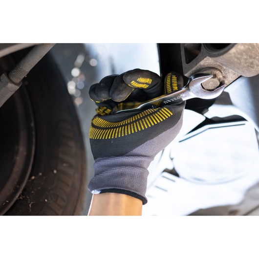 STANLEY FMMT13098-0 wrench held by gloved hand tightening bolt near car wheel, close-up photography.
