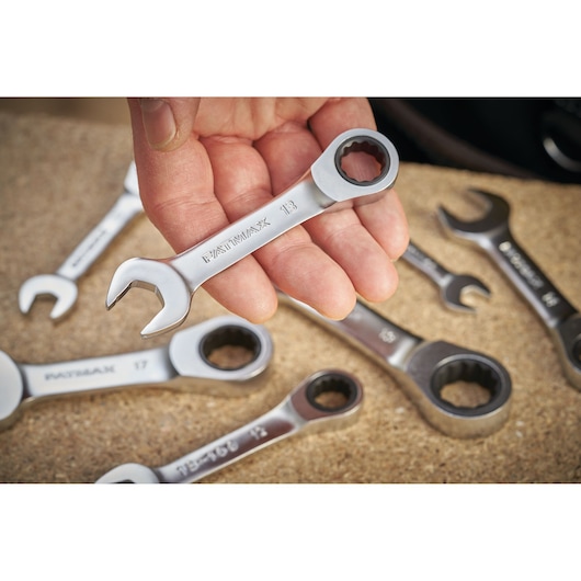 STANLEY FMMT13109-0 combination ratchet wrench set, close-up of a wrench held in hand, other wrenches on wood.