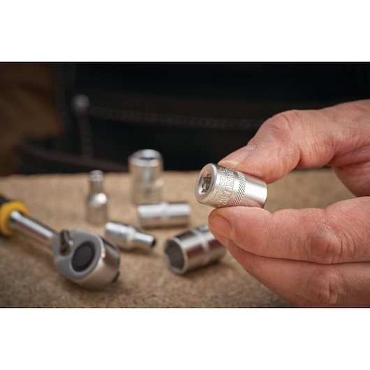 Photo of STANLEY FMMT17194-0 socket held by hand, with ratchet and sockets on work surface.