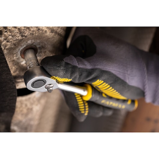 STANLEY FMMT17197-0 ratchet wrench in use, close-up showing hand with glove turning metal bolt.