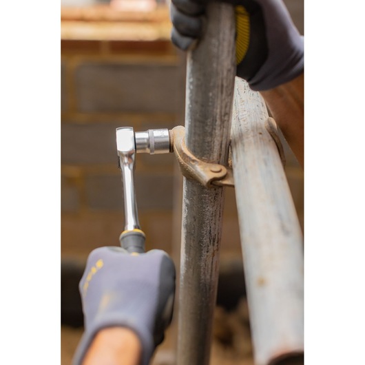 Photo of STANLEY FMMT82678-0 ratchet being used to tighten a metal pipe clamp in a construction setting.