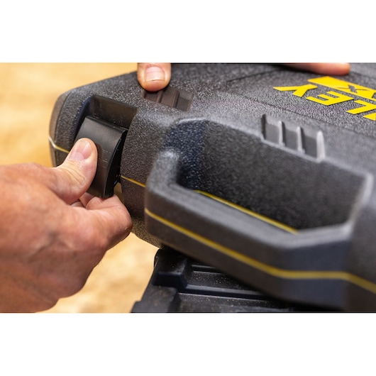 STANLEY FMMT82683-0 tool case latch close-up showing textured black plastic, yellow logo, and a hand operating the latch.