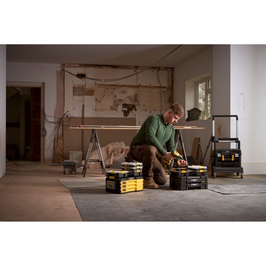 STANLEY FMMT98103-1 toolboxes and organizer in use on a construction site, worker kneeling beside them.