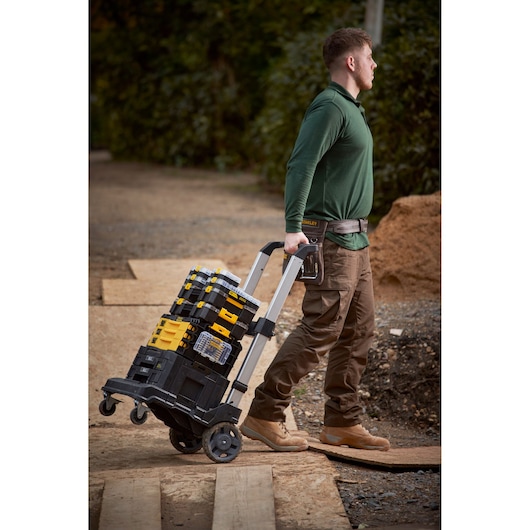 STANLEY FMMT98106-1 tool storage trolley with stacked boxes pulled outdoors by a person.