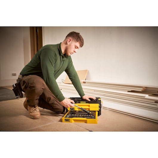 STANLEY FMMT98107-1 mechanic tool set in yellow case, shown open on floor with tools visible.