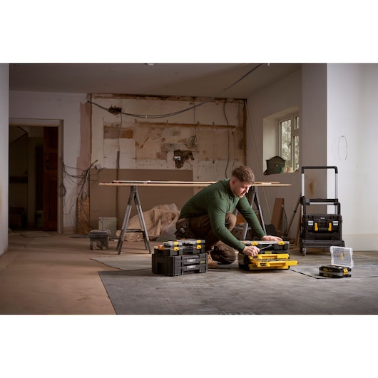 Photo of STANLEY FMMT98107-1 toolboxes and organizer boxes in a construction workspace, with a person organizing tools.